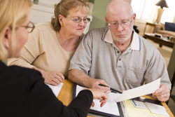 Senior Adult Couple Going Over Papers in Their Home with Agent.