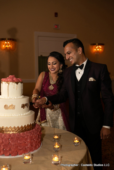 Cheerful Indian bride and groom cutting the cake.