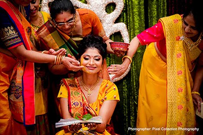 Indian wedding ritual of painting the bride with yellow turmeric paste