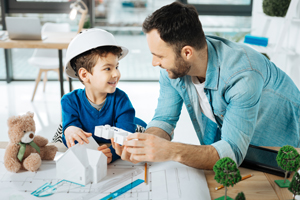 Cute boy and his son discussing 3D house model