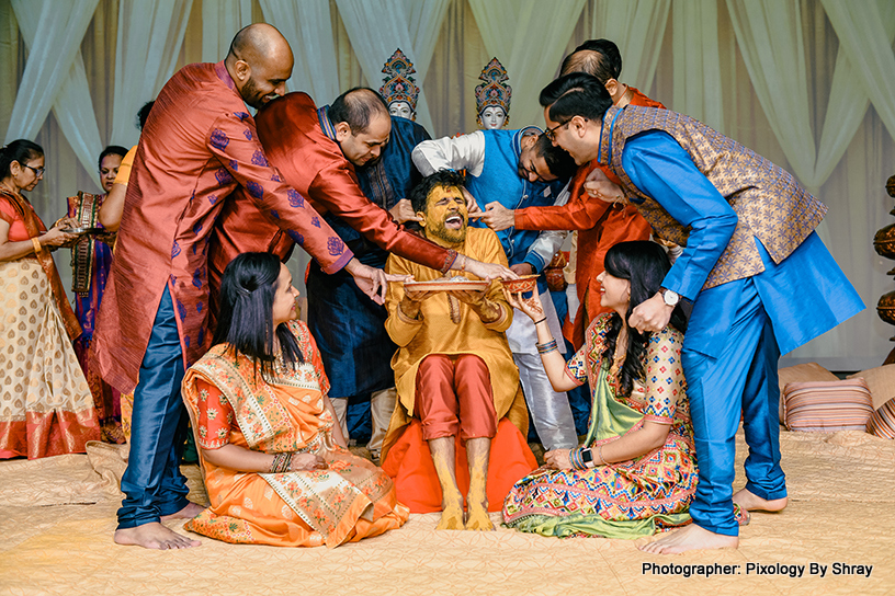 Indian wedding ritual of painting the groom with yellow turmeric paste