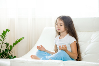 Happy kid girl doing yoga at home