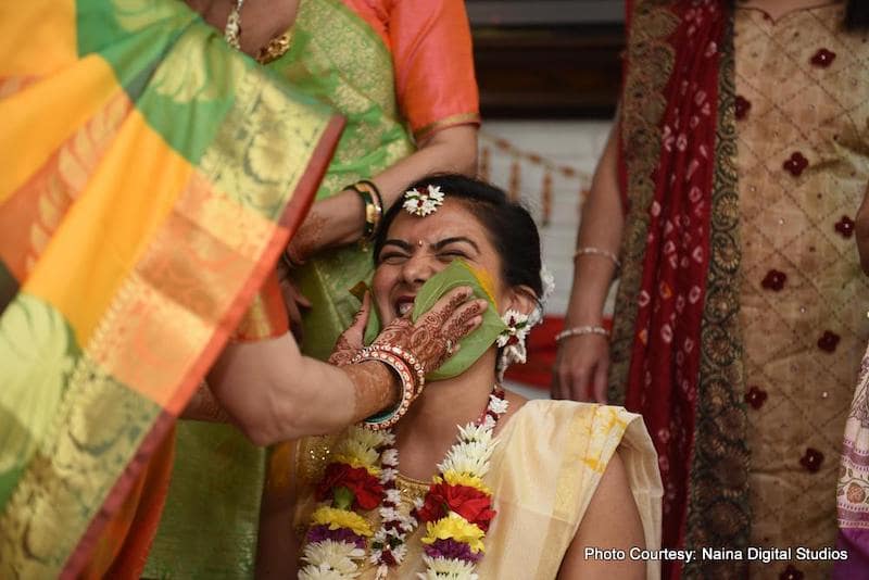 Indian bride mother applying haldi on bride's face