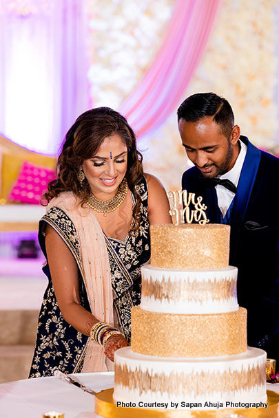Indian bride and groom cutting cake capture