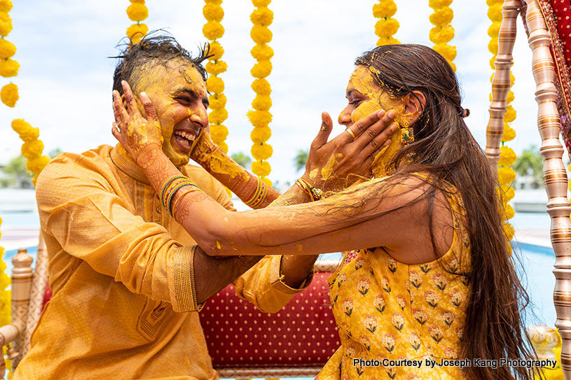 Groom and bride applying Turmeric on each other's face