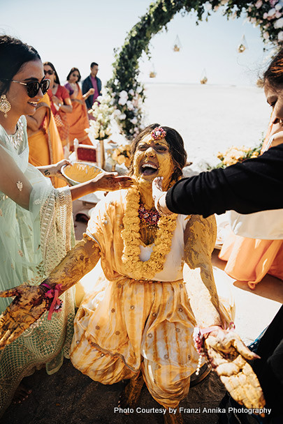 Indian wedding guest applying haldi on bride's face