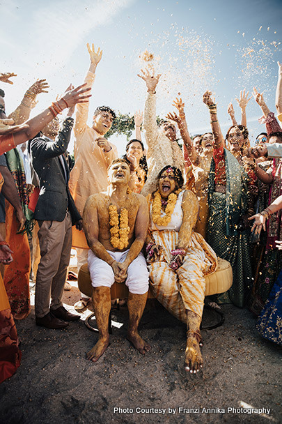Indian wedding guest showering flower petals on bride and groom