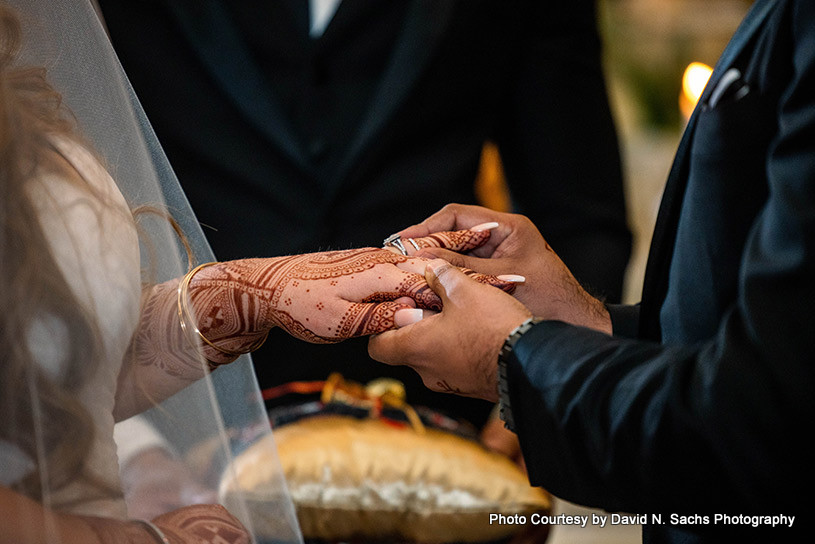 Indian groom putting ring on bride's finger