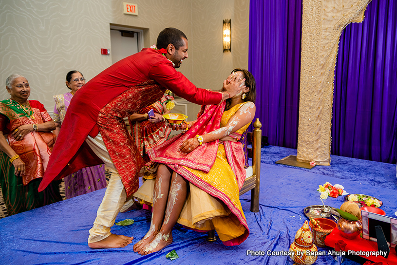 Brother of Indian bride applying haldi on her face