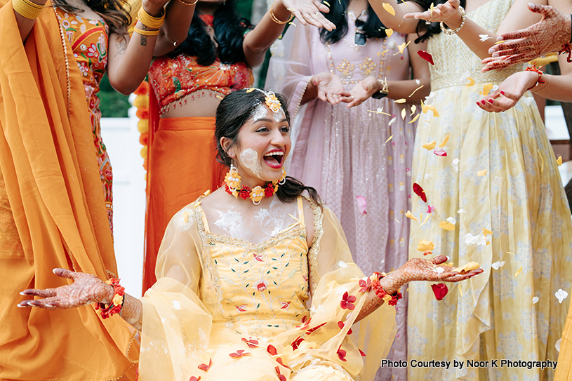 Family members of indian bride applying haldi on her face