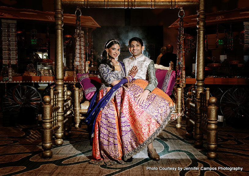 Indian bride and groom sitting on zula capture