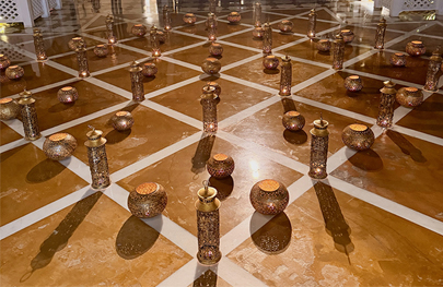 This image depicts a decorative arrangement of traditional Indian lamps (diyas or lanterns) on a marble floor, often seen during celebratory occasions. 