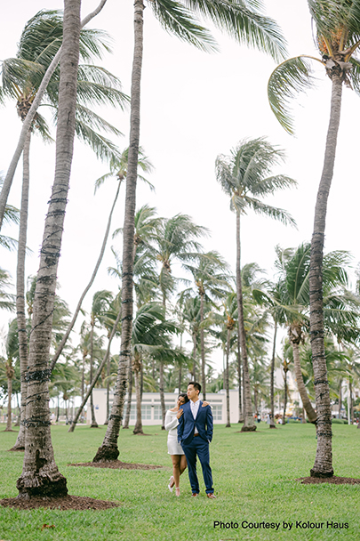 Navya and Eddy walking hand-in-hand among palm trees in Miami