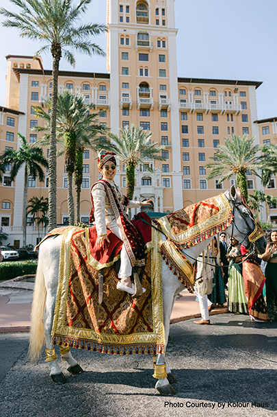 Eddy arriving on horseback for the baraat as Navya watches from a balcony during their wedding ceremony at Biltmore courtyard