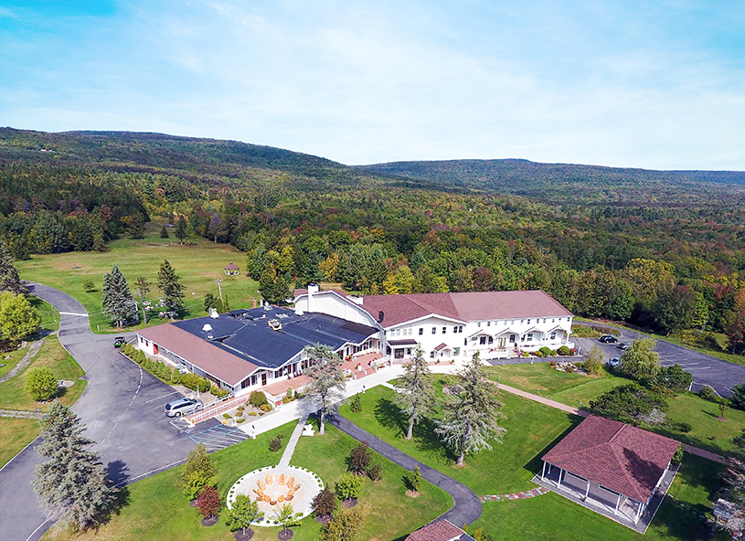 Aerial view of Peace Village campus with lodge‑style buildings and green surroundings