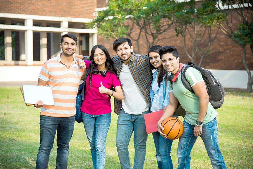 Cheerful Indian asian young group of college students or friends laughing together while sitting, standing or walking in campus