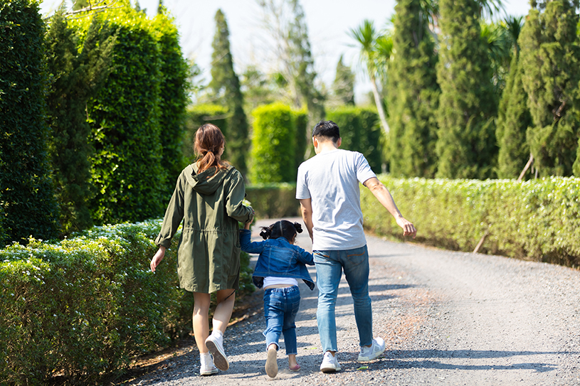Happy Asian family walking and holding hand together with children in the park.
