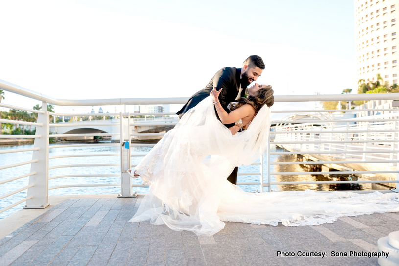 Close-up of the couple’s hands entwined, with natural scenery framing the shot