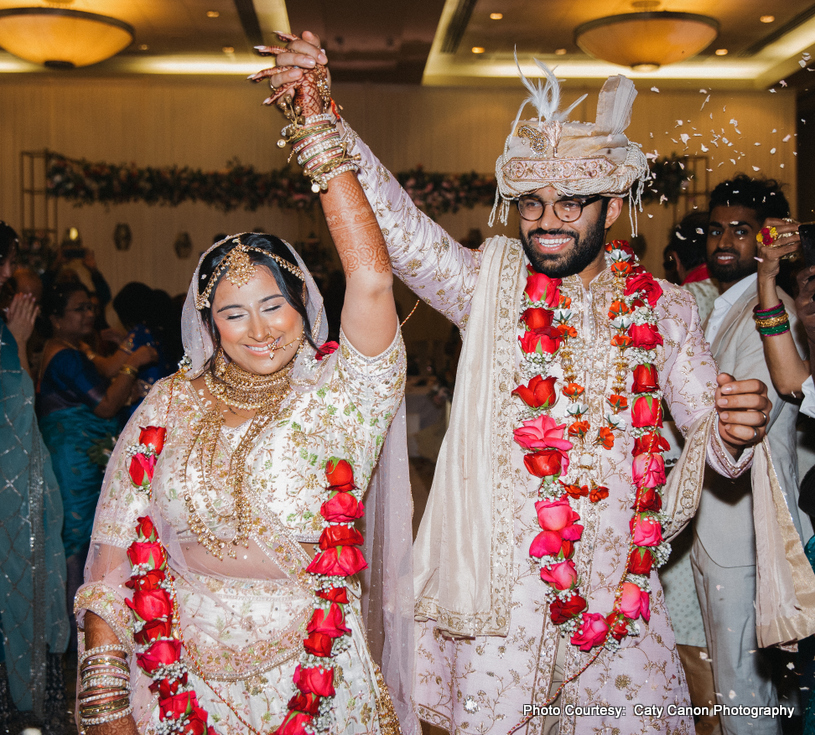 Ami and Vinny walking together in pastel traditional wedding attire