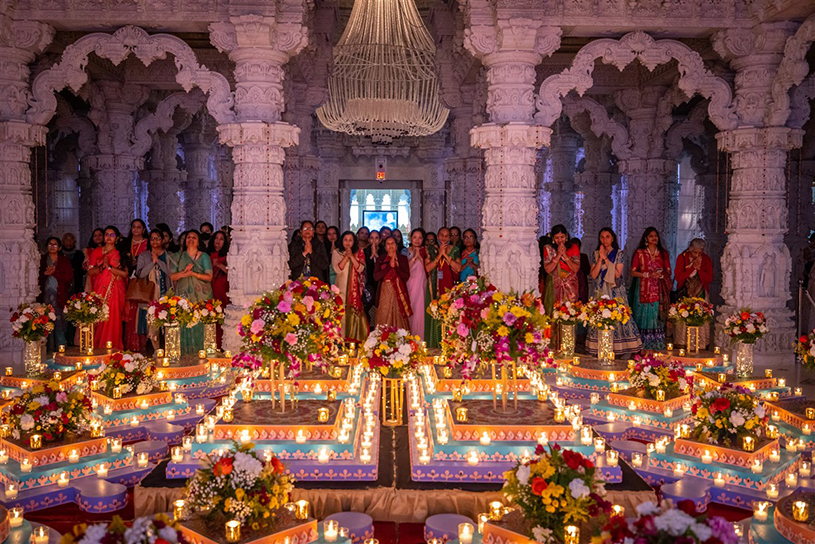 Devotees celebrating Diwali at BAPS Swaminarayan Akshardham in Robbinsville with traditional lamps and floral decorations