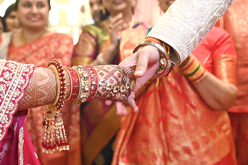 Close-up of Priyanka holding Aneesh’s hand during sacred wedding rituals in Prayagraj