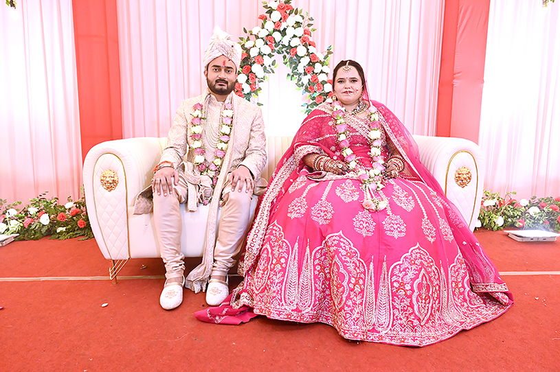 Aneesh and Priyanka seated together on wedding stage in traditional Indian attire during their Prayagraj wedding ceremony