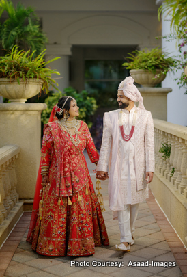 Tithi and Bhaumik walking hand in hand in traditional wedding outfits during Tampa celebration